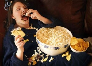 Femeie pe canapea care mananca junk food